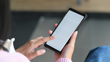 Cropped shot of woman hand while using a smartphone. Pointing finger on white blank screen.