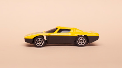 Fototapeta premium yellow little car. toy car on a beige background side view 