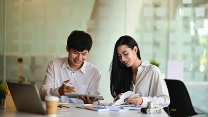 Business team while they are discussing about the projects. They are using tablet and colour guide on work desk.