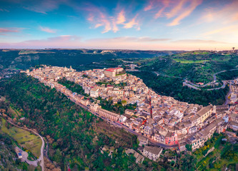 View from flying drone. Magnificent spring sunset in Ragusa town with Duomo San Giorgio - baroque Catholic church on background. Gorgeous evening scene of Sicily, Italy, Europe.
