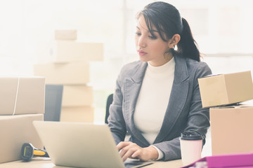 Online shopping SME entrepreneur or freelance working concept. Young asian women working laptop. Business owner working at home office packaging background.