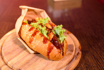 Big tasty hot dog on a wooden tray on the table. Unhealthy food.