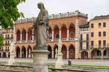 Fototapeta na wymiar Loggia Amulea in red brick and terracotta neo-Gothic style building, with double loggia facing Prato della Valle, Padua, Italy, 1860. View with statues in the square.