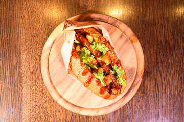 Big tasty hot dog on a wooden tray on the table. Unhealthy food.