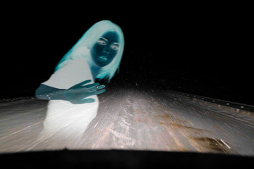 llustration of a ghost that appears in the headlights in front of a car driving on a night highway