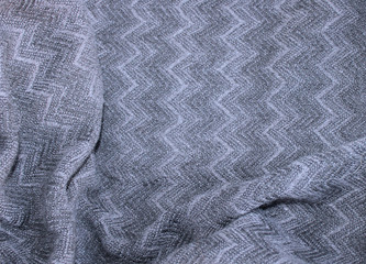 Woolen grey fabric with a herringbone pattern. Material with pleats. Warmth and comfort.