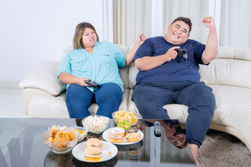 Fat Asian couple playing video games cheerfully