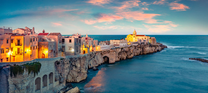 Exotic evening cityscape of Vieste - coastal town in Gargano National Park, Italy, Europe. Coloful spring sunset on Adriatic sea. Traveling concept background.