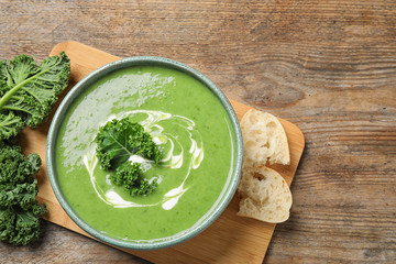 Tasty kale soup served on wooden table, flat lay