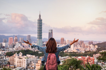 Naklejka premium Young woman traveler looking beautiful cityscape at sunset in Taipei, Travel lifestyle concept