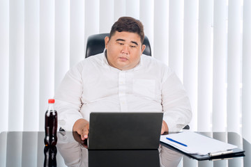 Fat businessman working at his laptop seriously