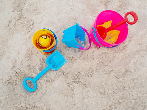 Colorful plastic children's beach toys on sand beach in summer day. Kids toys, bucket, shovel.