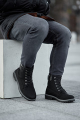 sitting man legs in black suede plain boots