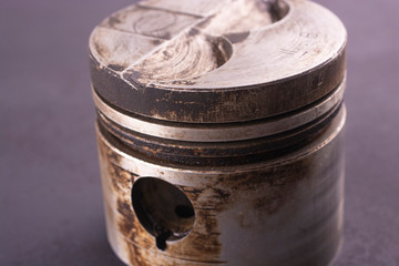 Old used piston of a car engine closeup.
