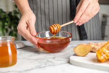 Woman with tasty honey at marble table, closeup