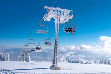Skiers on chairlift at mountain ski resort with beautiful winter landscape in the background