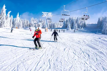 Fotobehang People enjoying skiing and snowboarding in mountain ski resort with beautiful winter landscape in the background © Drpixel