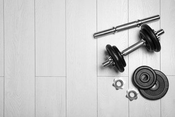 Gym equipment on wooden floor, flat lay. Space for text