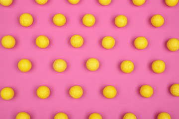 Many delicious lemon drops on pink background, flat lay