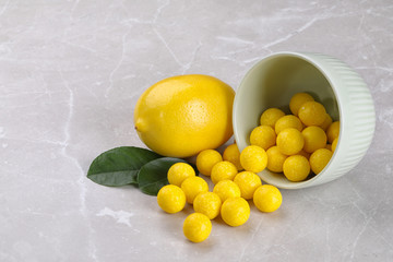 Tasty candy drops and fresh lemon on grey marble table