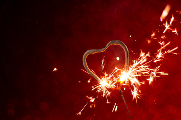 Heart shape Bengal light sparkle on red abstract background. Holiday greeting card, background for...