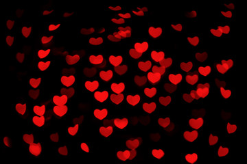 Fototapeta na wymiar Abstract beautiful romantic picture of blur brightness red colored of swirling heart shaped bokeh on black from ornamental lights flickering. Background for Valentine’s day or Love or Romance concept.