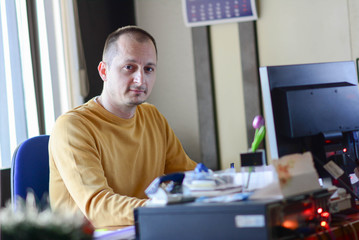 Portrait of middle-aged man sitting at his desk in the office. Image of a handsome positive cheery optimistic businessman, using desktop computer sit at the table.