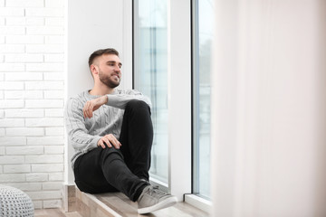 Handsome young man near window at home