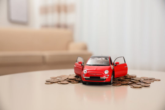 Miniature automobile model and money on table indoors. Car buying
