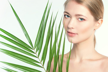 Fototapeta premium Natural organic skin care, the concept of harmony with nature, green long fern leaves grass near the face. portrait of beauty ladies. Young beautiful woman with clean sparkling skin of face and body