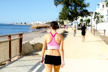 Runner, sportswoman, healthy lifestyle, running woman on the beach, short sports black pants and sports bra, beautiful weather and sea, healthy body and sports enthusiasm cardio training endorphins