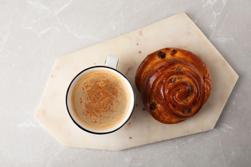 Delicious coffee and bun on marble table, top view. Sweet pastries