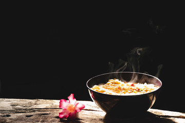 Steam and smoke Instant noodles in bowl on wooden table and nature light and black background, selective focus. It is a convenient and inexpensive food, but eating often is not good for health.