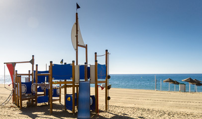 Playground on the sandy beach Spain. Mediterranean coast. Beautiful weather clear blue sky. Fun for children with parents on the beach. Always ready for tourists.