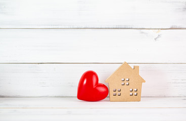 Red Heart Shaped with Home over white wood background. Symbol for love , family concept with copy space.