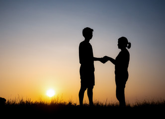 Fototapeta na wymiar Silhouette of lovely couple holding by hands on beautiful sunset