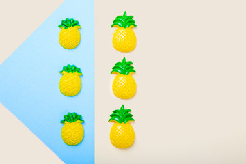 Flat, copy space. Toy pineapples on a beige and blue background. Children's toys made of polymer clay.