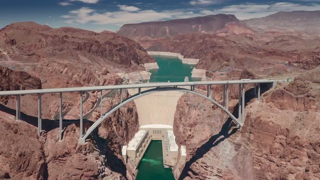 The flight over the Colorado river canyon. Crossing Hoover Dam Bypass Bridge with vehicles driving it. Coming closer to the famous Dam behind the bridge and the reservoire with turquoise water in it