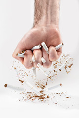 The concept of nicotine addiction and anti-Smoking. A man's fist squeezes the cigarettes, breaking...