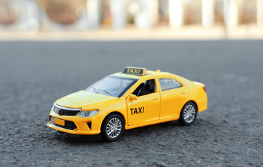 Fototapeta na wymiar Yellow taxi car model on city street