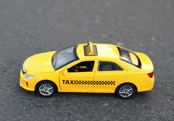 Fototapeta na wymiar Yellow taxi car model on city street