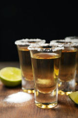 Mexican Tequila shots, lime and salt on wooden table