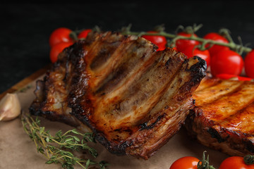 Tasty grilled ribs with tomatoes on table, closeup