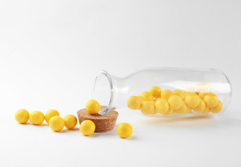 Tasty lemon drops and bottle on white background