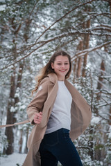 Portrait of a young beautiful girl in a snow-covered pine forest. A girl in a fabulous winter forest with white trees and abundant snow