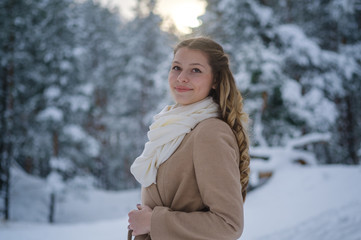 Portrait of a young beautiful girl in a snow-covered pine forest. A girl in a fabulous winter forest with white trees and abundant snow