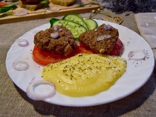 homemade country dinner on a white plate of vegetables with cutlets and mashed potatoes. selective focus