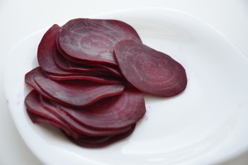 beautifully sliced beetroot stacked on top of each other, round slices of raw and healthy greenery full of vitamins and minerals, vegan and vegetarian healthy food, white background