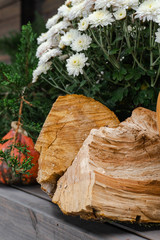 close-up wooden stack wall background, and autumn white flowers with green grass, firewood pattern tree