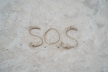 Sos sign drawn on beach sand.